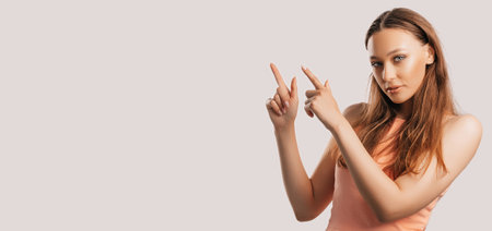 Portrait of a smiling girl pointing finger to the side at on a white isolated background. Positive woman points to an idea, a place for advertisingの写真素材