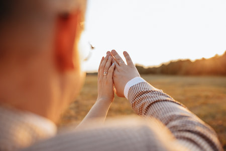 Bride and groom on wedding day hug and show rings at sunsetの写真素材