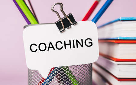 Text COACHING on a white sticker with office stationery background. Flat lay on business, finance and development conceptの写真素材