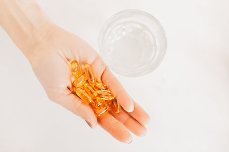 Girl holding capsules pills of dietary supplements with omega and amino acids on a white background. Health care concept, dietの写真素材