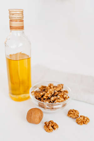 Walnut or olive oil in glass of bottle, whole big peeled walnut kernel with thin shell on white background. healthy food for brain. Fresh walnuts background nut conceptの写真素材
