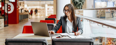 Girl works on a laptop in the workplace. Successful business woman creates a startup and makes decisions.の写真素材