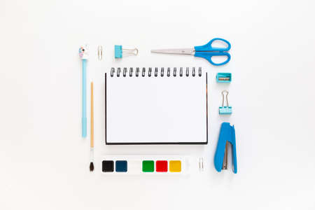 Top view of modern white blue office desktop with school supplies and stationery on table around empty space for text. Back to school concept flat lay with mockupの写真素材