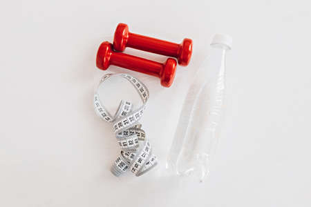 A centimeter, a bottle of water and red dumbbells. Health care, diet and sport conceptの写真素材