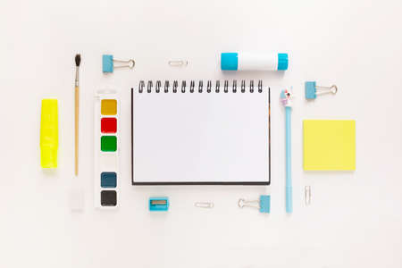 Top view of modern white, blue, yellow office desktop with school supplies and stationery on table around empty space for text. Back to school concept flat lay with mockupの写真素材