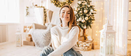 Beautiful cheerful happy young girl with christmas gifts on the floor near the new year tree at homeの写真素材