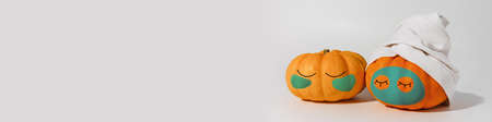 Pumpkin with facial mask and towel isolated on white background. Space for text mockup Spa and Halloween conceptの写真素材