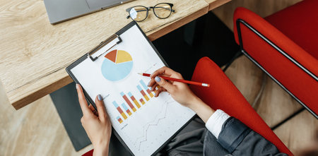 Business woman checks charts and refreshes financial progress. The girl analyzes the business model in the workplace.の写真素材