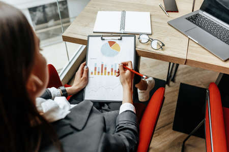 Business woman checks charts and refreshes financial progress. The girl analyzes the business model in the workplace.の写真素材