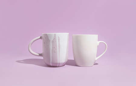 Two designer mug on a solid purple background. Handmade ceramics conceptの写真素材