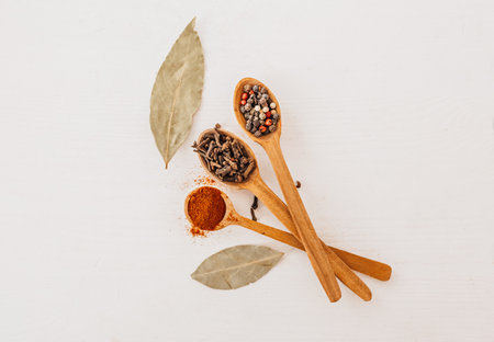 Spices in a wooden spoon. Herbs, curry, saffron, turmeric, cinnamon, bay leaf, peppers for cooking on a white backgroundの写真素材