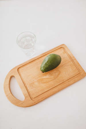 Avocado and a glass of water on a wooden board. Health care and diet conceptの写真素材