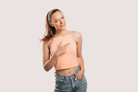 Portrait of a smiling girl pointing finger to the side at on a white isolated background. Positive woman points to an idea, a place for advertisingの写真素材