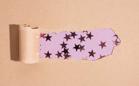 Torn kraft paper with purple star shape glitter on violet background. Flat lay style for holiday, birthday, wedding, new year, christmas, party, celebration conceptの写真素材