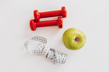 Green apple, centimeter and red dumbbells. Health care, diet and sport conceptの写真素材