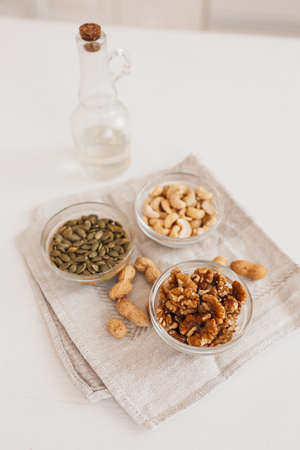 Nuts and vinegar on a linen tea towel on a white table. Walnuts, cashews and pumpkin seeds for proper nutrition. healthy foods and nutrients for the brain and bodyの写真素材
