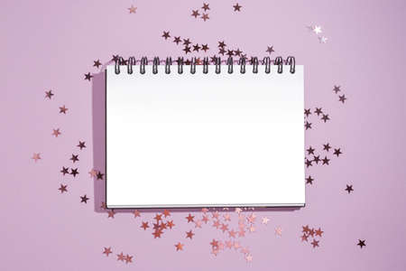 Notepad with mockup on purple star shape glitter on violet background. Flat lay style for holiday, birthday, wedding, new year, christmas, party, celebration conceptの写真素材