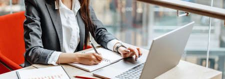Girl works on a laptop in the workplace. Successful business woman creates a startup and makes decisions.の写真素材