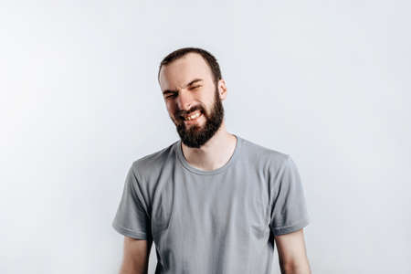 Handsome young brunette man frowning and closing eyes, angry on white background with space for advertising mock upの写真素材