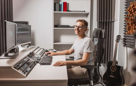 Man working in music studio using computer wearing glasses. Sound engineer working and mixing track. Programmer watching at display of it while listening music. Technology conceptの写真素材