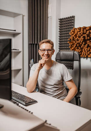 Man working in music studio using computer wearing glasses. Sound engineer working and mixing track. Programmer watching at display of it while listening music. Technology conceptの写真素材