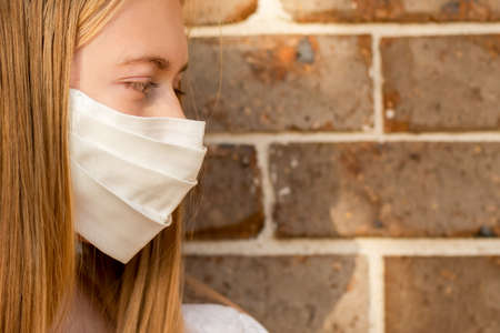 A girl wearing handmade cotton face mask to prevent spreading of the viruses. Coronavirus and COVID-19 Concept.の写真素材