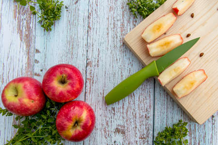Organic ripe apples on a wooden table and apple slices on wooden board. Fresh cut apple healthy snack. Cooking ingredients. Harvest.の写真素材