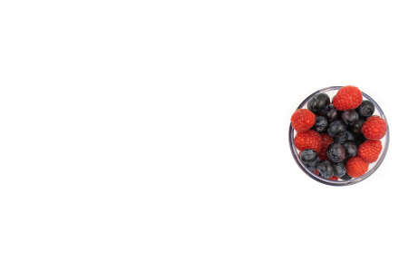 Blueberries amd raspberries in a transparent bowl on a white background. Healthy lifestyle concept.の写真素材