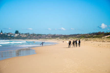 Bendalong, Australia 2020-06-06 Young adult surfers in wetsuits carrying surfboards on a sandy beachのeditorial素材