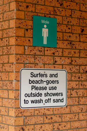 Notice on a brick wall of men public toilet amenities - Surfers and beach-goers please use outside showers to wash off sandの写真素材