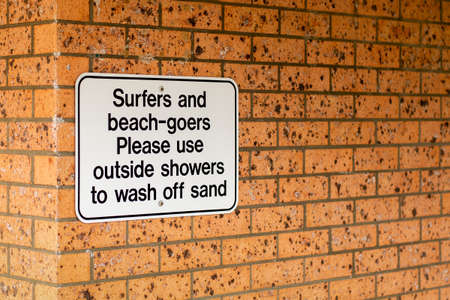 Notice on a brick wall - Surfers and beach-goers please use outside showers to wash off sandの写真素材