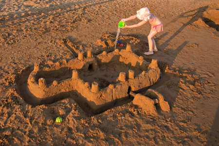 Little girl buiding big sandcastle on a sandy beach. Summer vacation conceptの写真素材