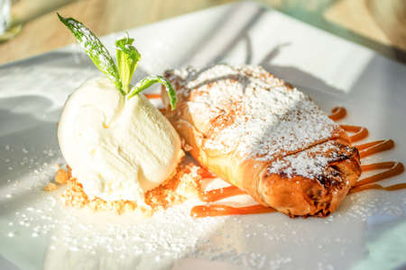 Bougatsa pastry dessert. Salted caramel and custard encased in filo pastry finished with icing sugar and vanilla ice creamの写真素材