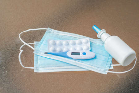 Coronavirus concept. Disposable masks, thermometer, tablets in a blister and treatment medicineの写真素材