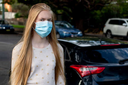 A girl wearing disposable face maskwalking in the street. Coronavirus and COVID-19 Conceptの写真素材