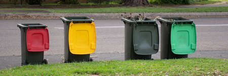 Australian garbage wheelie bins with colourful lids for recycling and general household waste lined up on the street kerbside for council rubbish collectionの写真素材