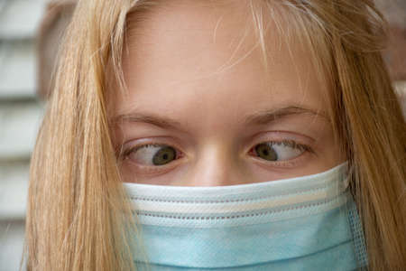 A girl wearing disposable surgical face mask making funny silly face. Coronavirus conceptの写真素材