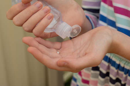 A girl in a striped dress applying hand sanitizer on her hands to protect from the virusの写真素材