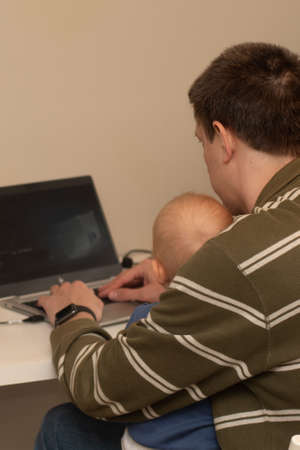 Coronavirus concept. Close op of hands of a man working from home with the baby on his laps.の写真素材