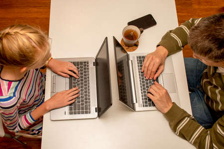 Coronavirus concept. Working and learning from home - father and daughter sharing one table.の写真素材