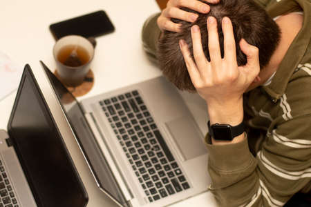 Coronavirus concept. Working from home - family sharing one table. Man looking overwhelmed and tiredの写真素材