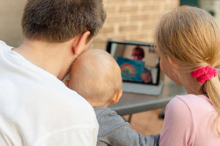 Family video chat - a man with two children using tablet for communicationの写真素材
