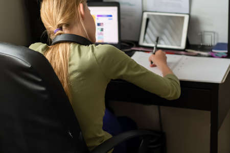 Stay home: Teenage girl sitting with laptop, notebook and tablet - online learning from home. Self...