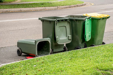 Australian garbage wheelie bins with colourful lids for recycling and general household waste on the street kerbside after council rubbish collectionの写真素材