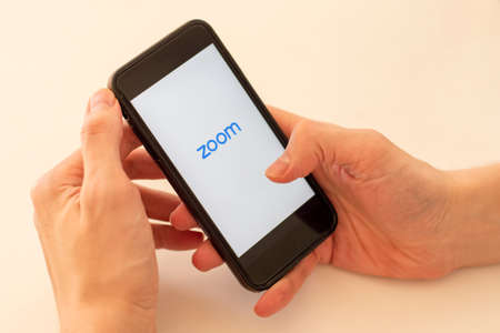 Sydney, Australia - 2020-04-04 Hands holding a smart phone with zoom cloud meetings application. Selective focusのeditorial素材