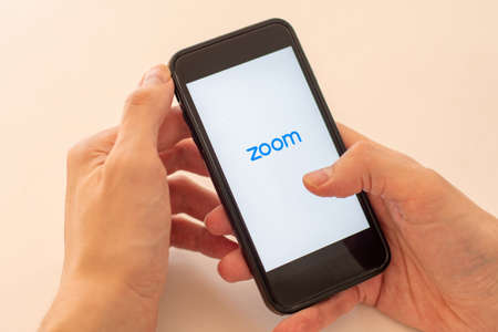 Sydney, Australia - 2020-04-04 Hands holding a smart phone with zoom cloud meetings application. Selective focusのeditorial素材