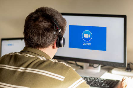 Sydney, Australia - 2020-04-06 Man woth headphones looking on a monitor with zoom cloud meetings...