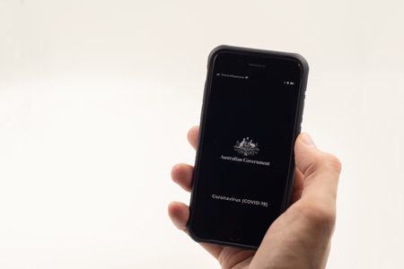 Sydney, Australia - 2020-04-16 Hand holding a phone with Coronavirus Australia app. Australian Government indtroduced an app with with official information and advices about COVID-19 pandemic.のeditorial素材