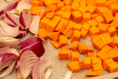 Vegetables - pumpkin and red onion - on a tray prepared for roasting in the oven. Healthy cooking.の写真素材