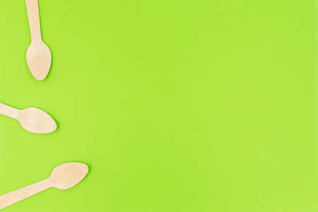 Eco friendly disposable cutlery utensils on green background. Bamboo wooden tea spoons. Zero waste conceptの写真素材